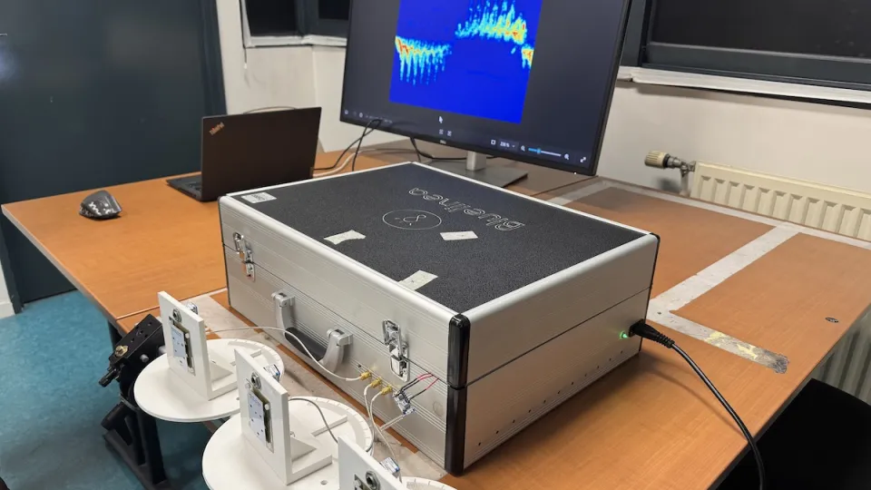 Photo du dispositif de détection de mouvement par radar : sur une table sont posés des capteurs et une valise de matériel reliés à un ordinateur